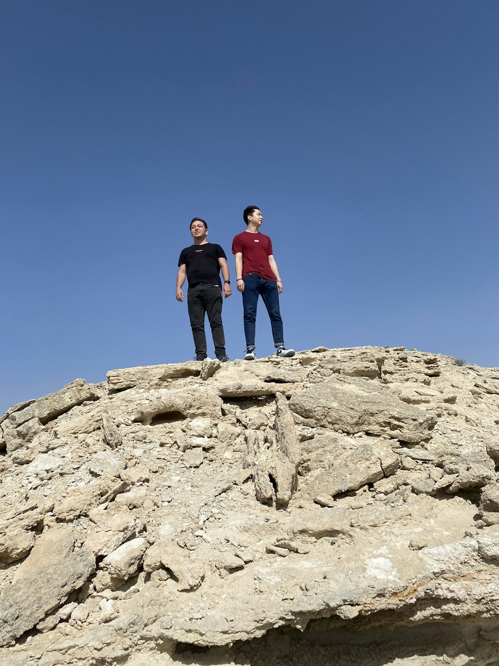 two men standing on top of a rocky mountain