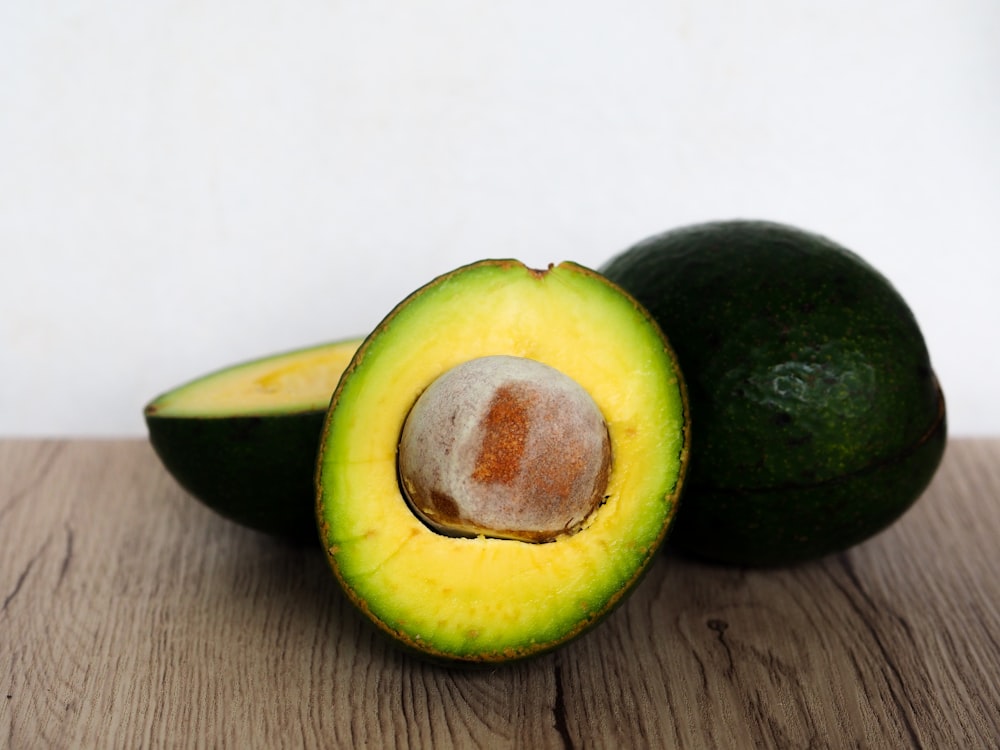 an avocado cut in half on a wooden table