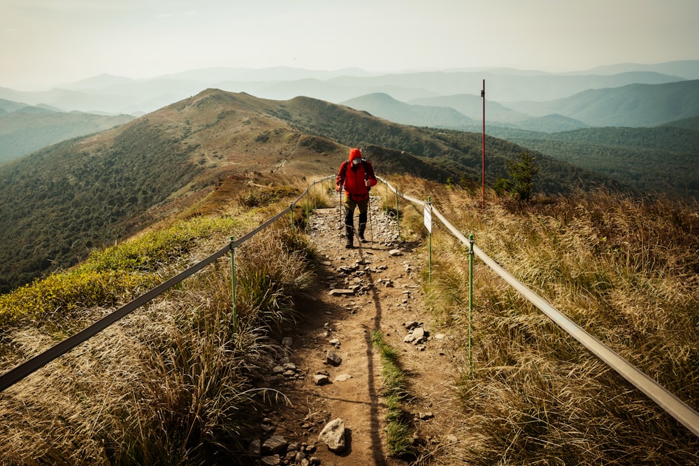 a man in a red jacket walking up a hill