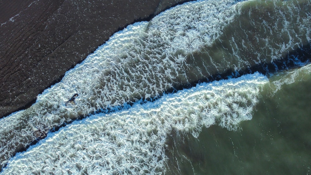 an aerial view of a beach with waves coming in