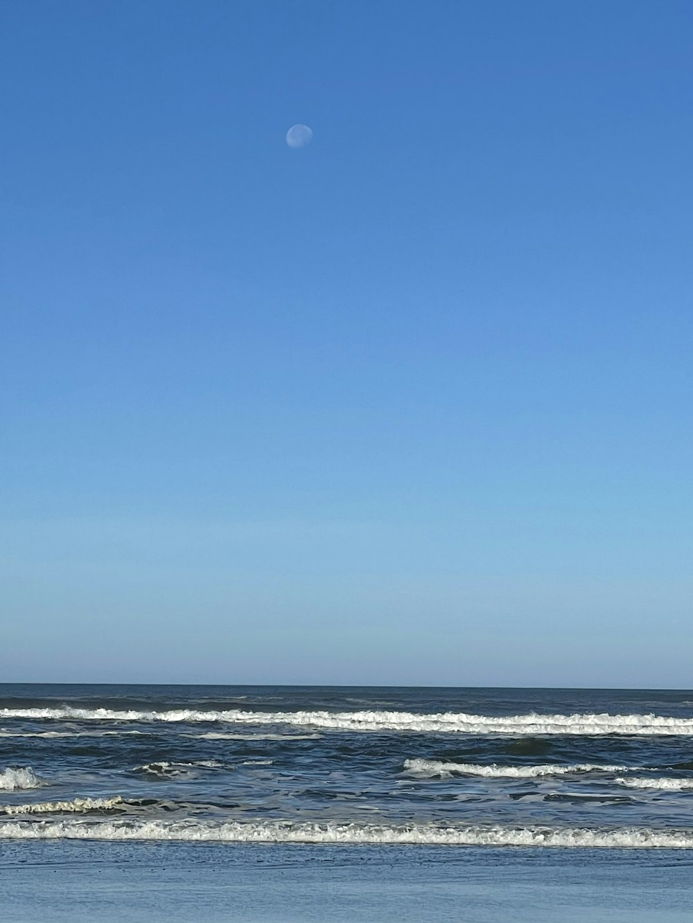 a person walking on the beach with a surfboard