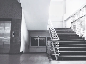 Elegant staircase with integrated red-themed home lift in a modern minimalist house