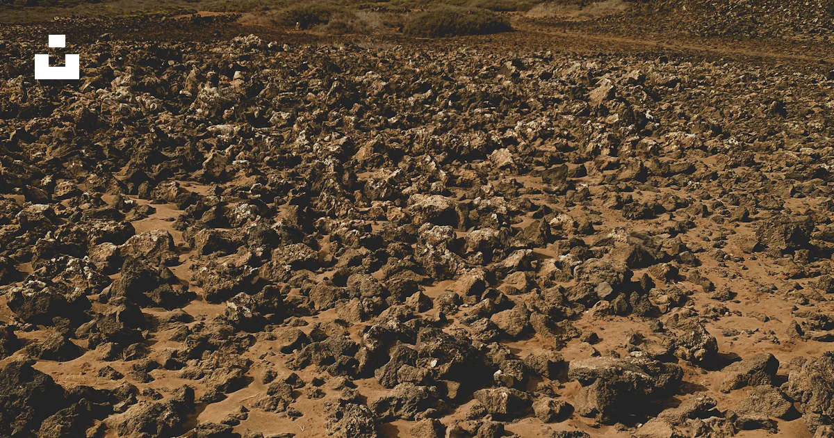 A field with rocks and a hill in the background photo – Free Wallpaper ...