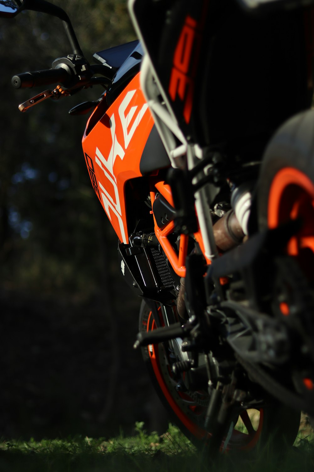 an orange and black motorcycle parked in the grass