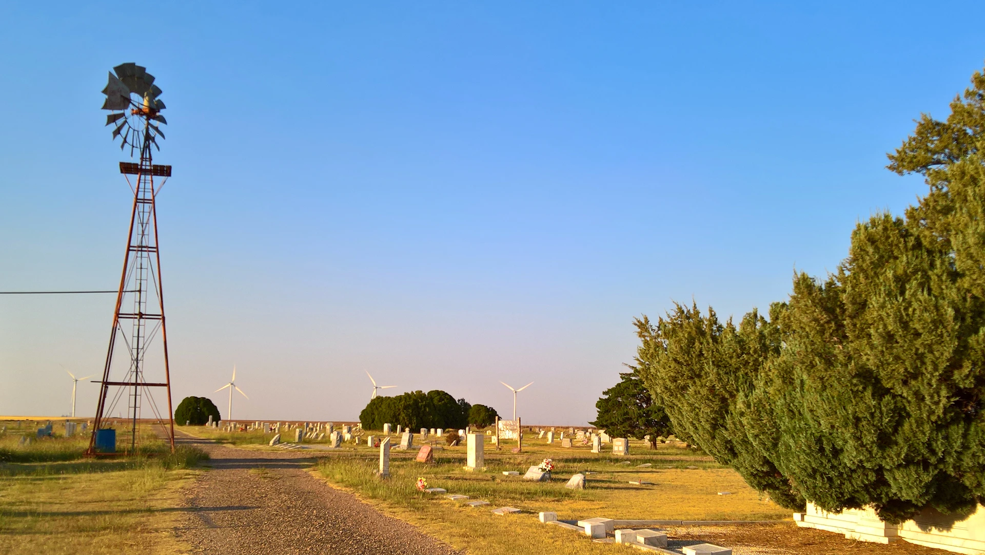 a windmill in a field next to a dirt road