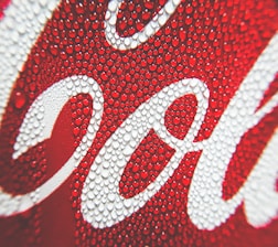 Close-up view of condensation droplets on a red and white surface with cursive lettering.