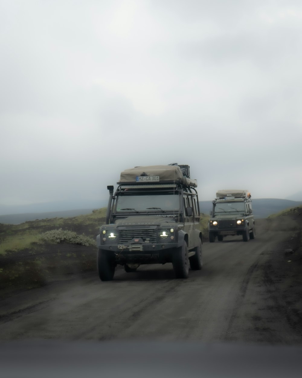 a couple of trucks driving down a dirt road