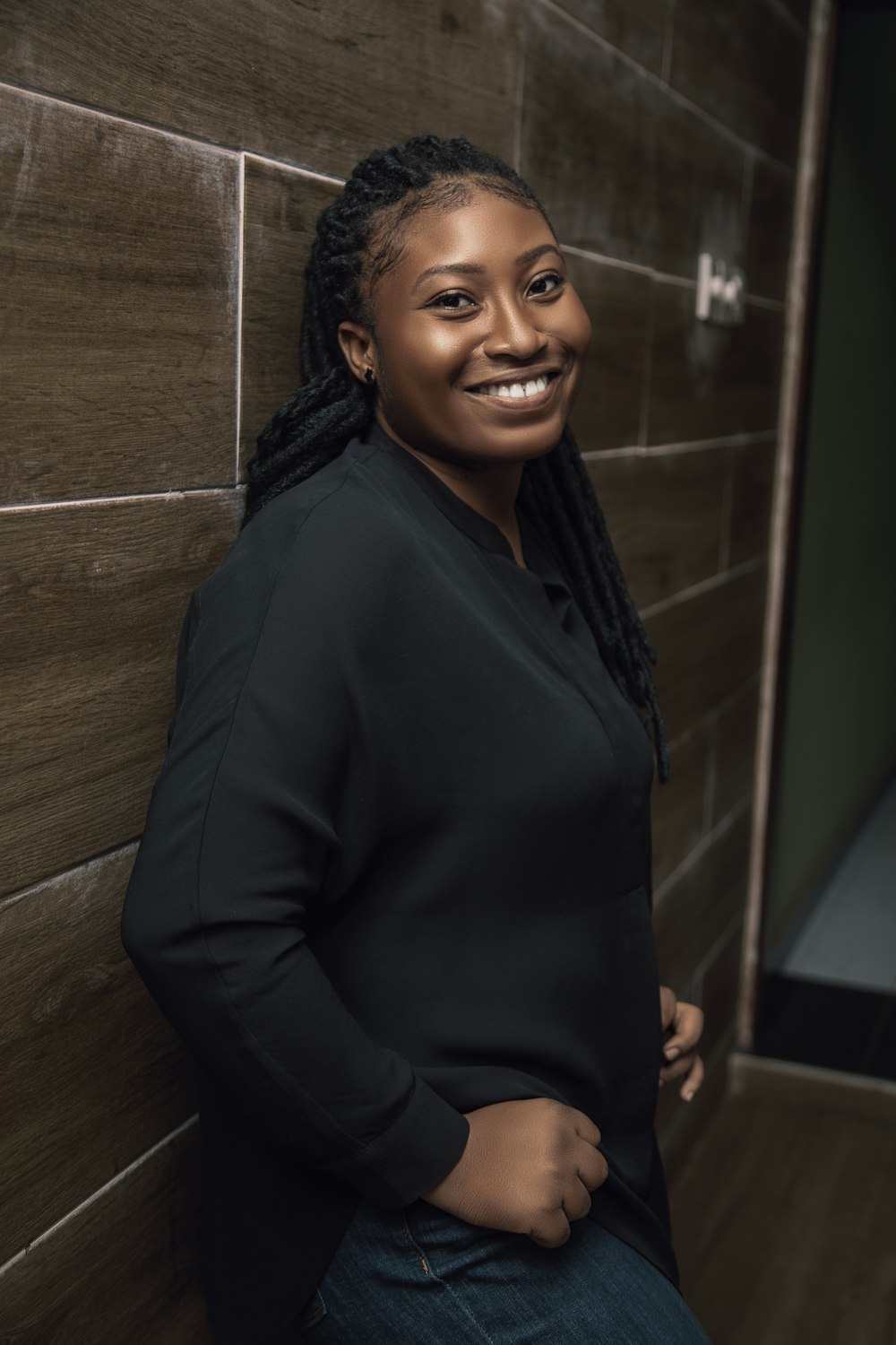 a smiling woman leaning against a wall