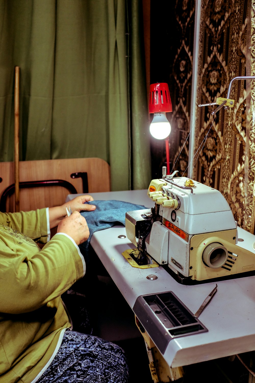 a woman sitting at a table working on a sewing machine