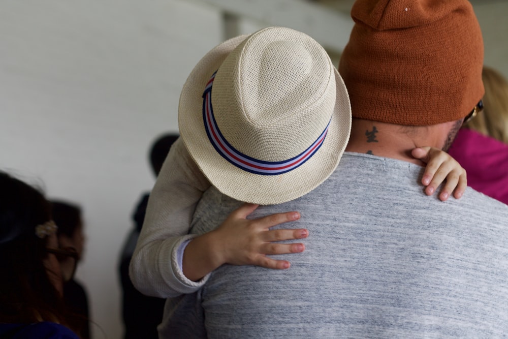 a man in a hat hugging a child