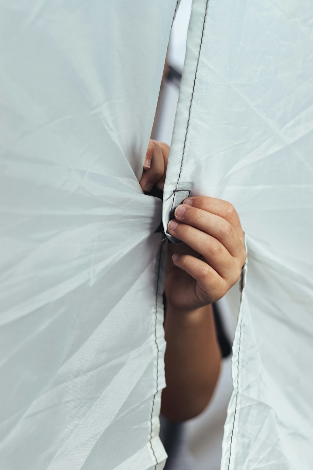 a person hiding behind a white sheet with their hands