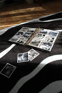 A serene photo of an old photo album open on a wooden table, sunlight softly illuminating the pages filled with memories.