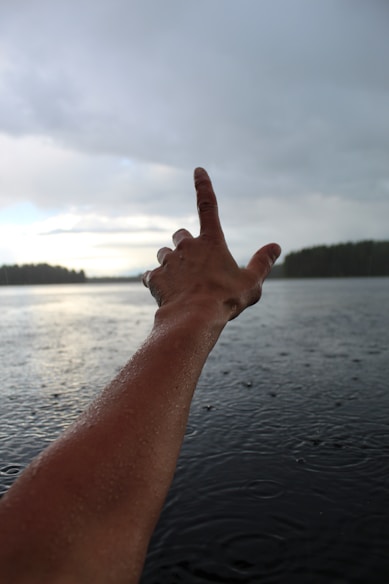 a person's hand reaching out towards the water