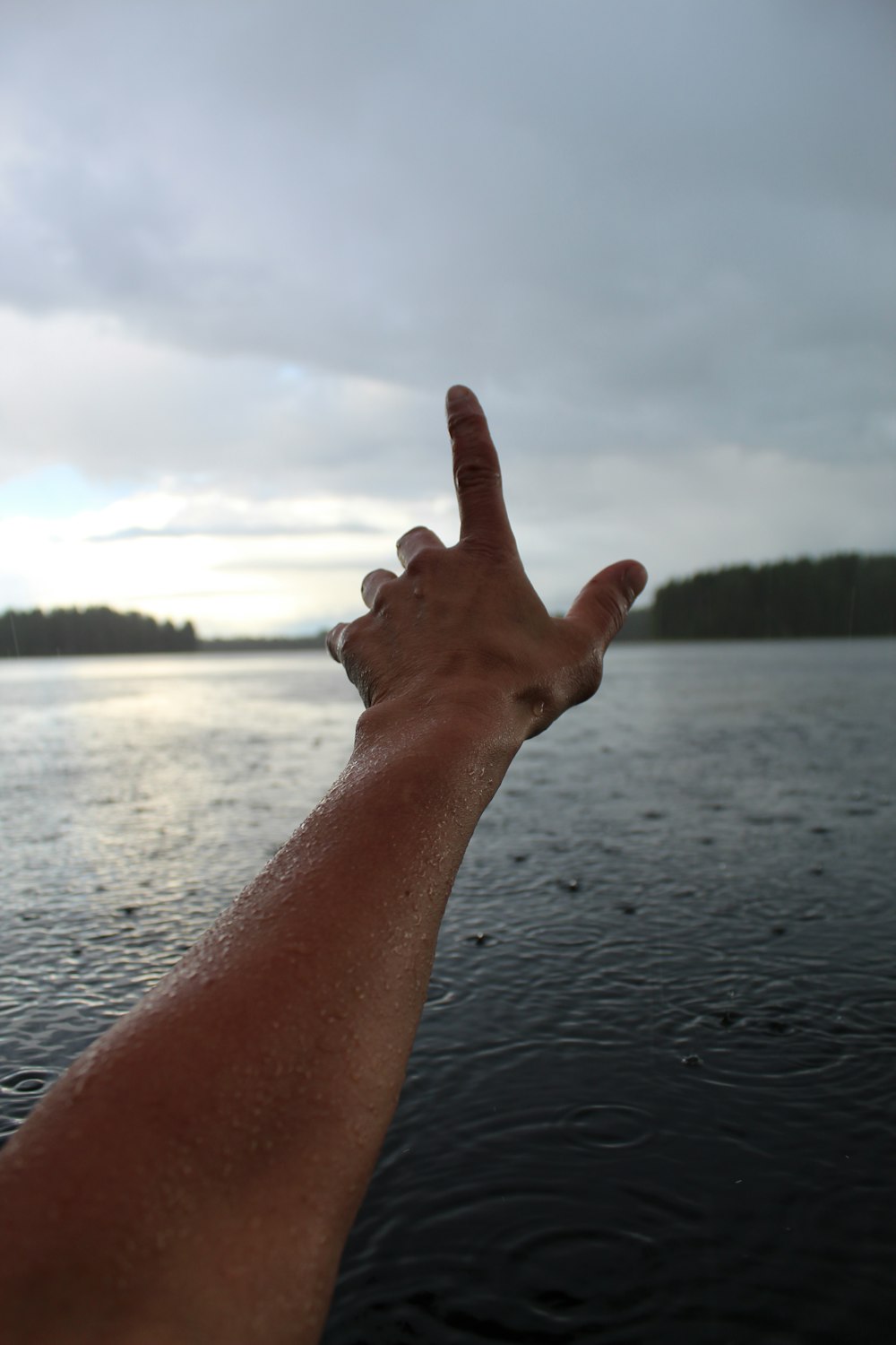 a person's hand reaching out towards the water