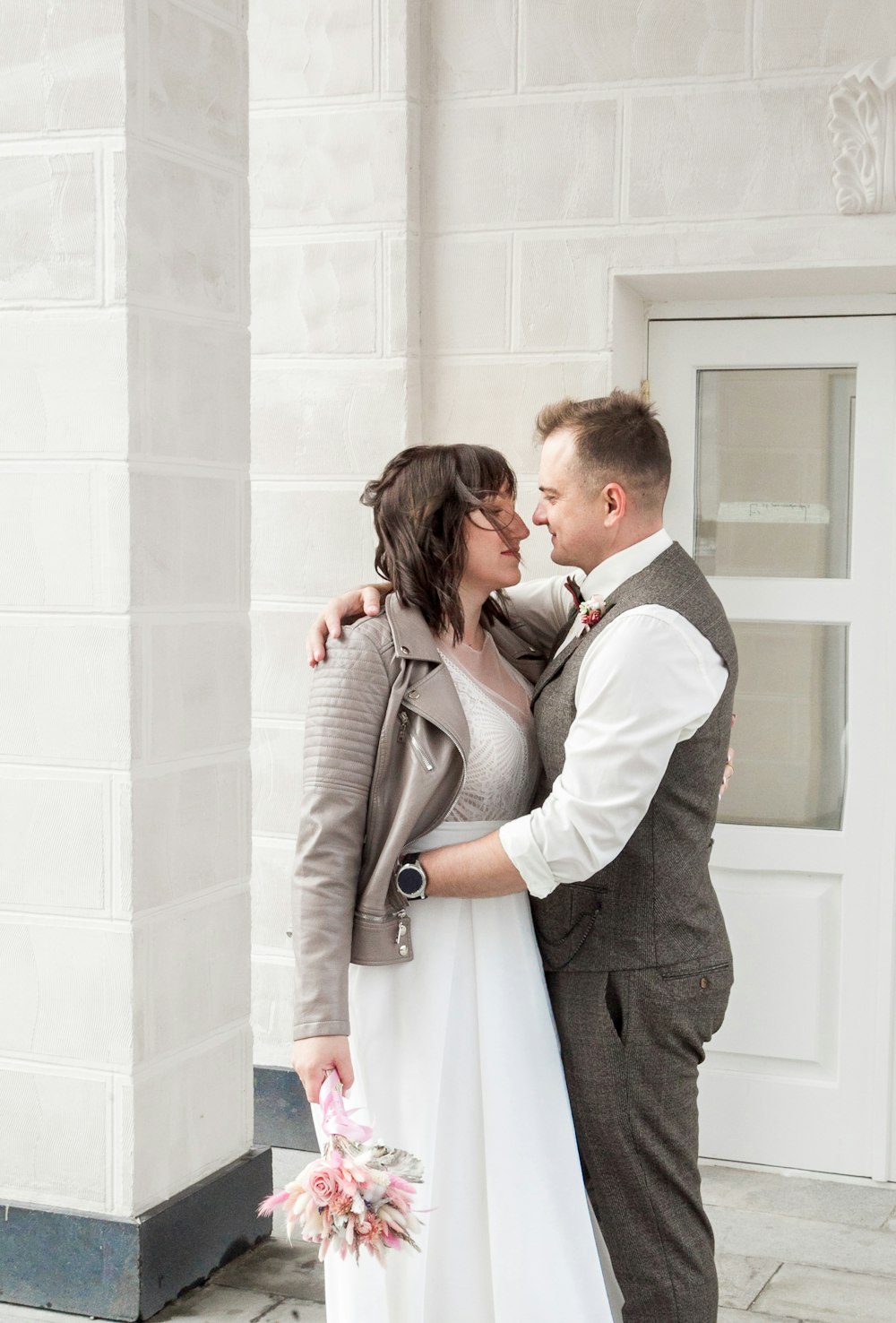 a man and a woman standing next to each other in front of a building