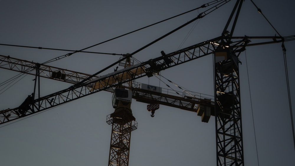 a tower crane is seen against a dark sky