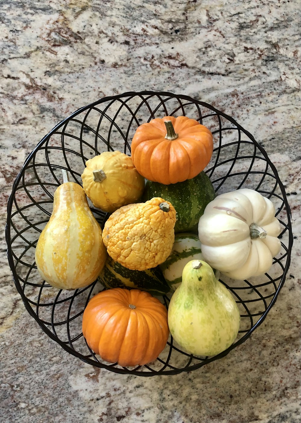 a wire bowl filled with different types of vegetables