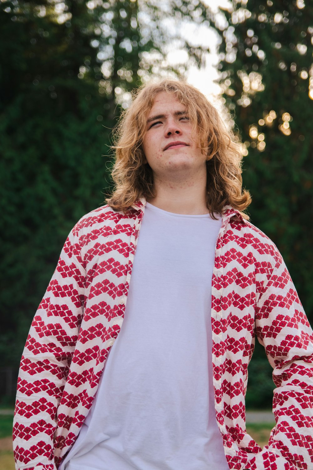 a man with long hair wearing a red and white sweater
