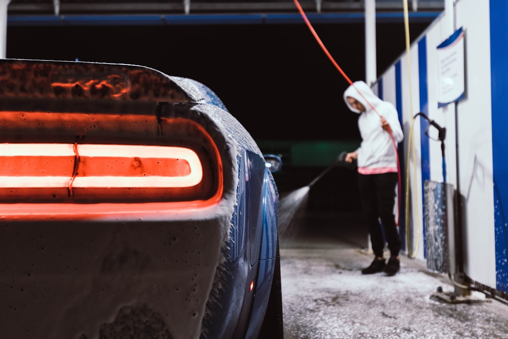 a woman in a white hoodie is washing a car