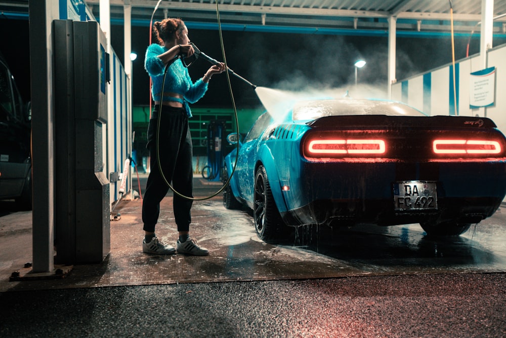 a woman washing a car with a hose
