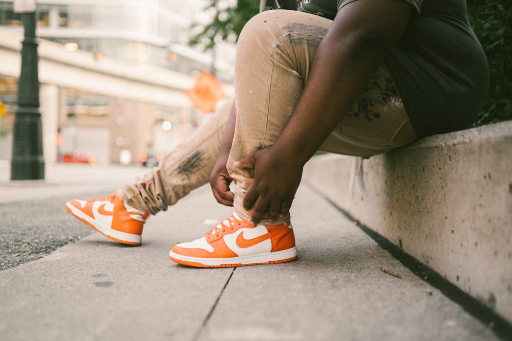 a man sitting on a curb tying his shoes