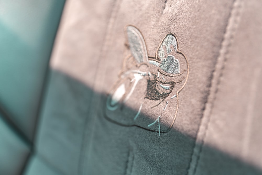 a close up of a car seat with a bug embroidered on it