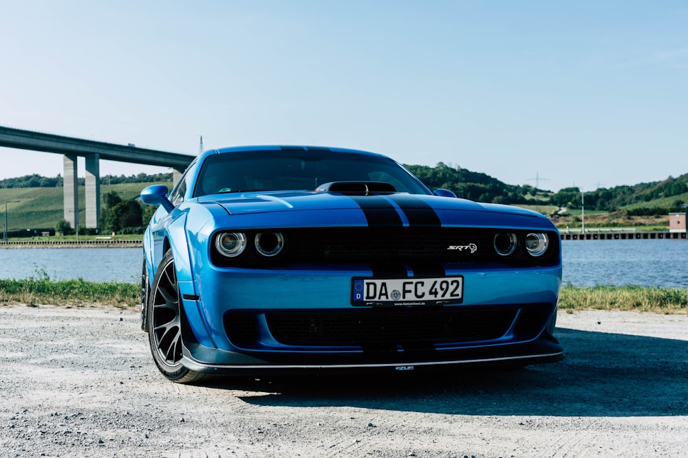 a blue sports car parked in front of a bridge