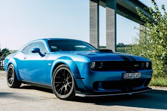 a blue sports car parked in front of a bridge