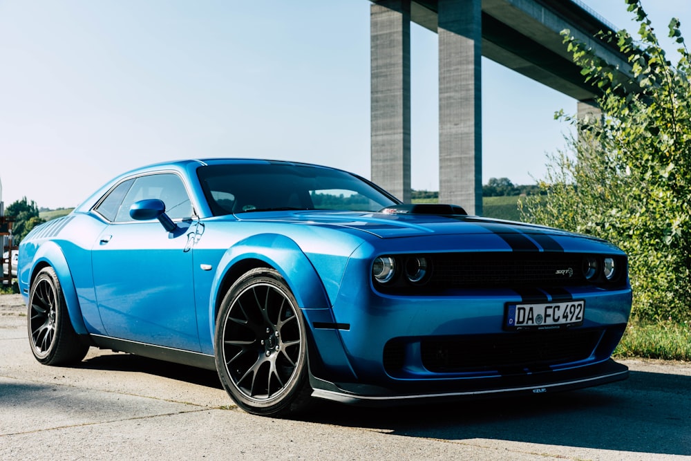 a blue sports car parked in front of a bridge