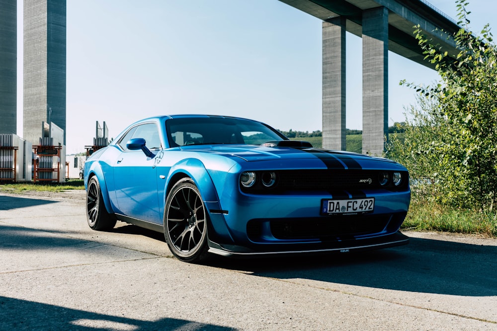 a blue sports car parked under a bridge