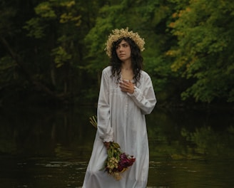 a woman in a white dress standing in a river