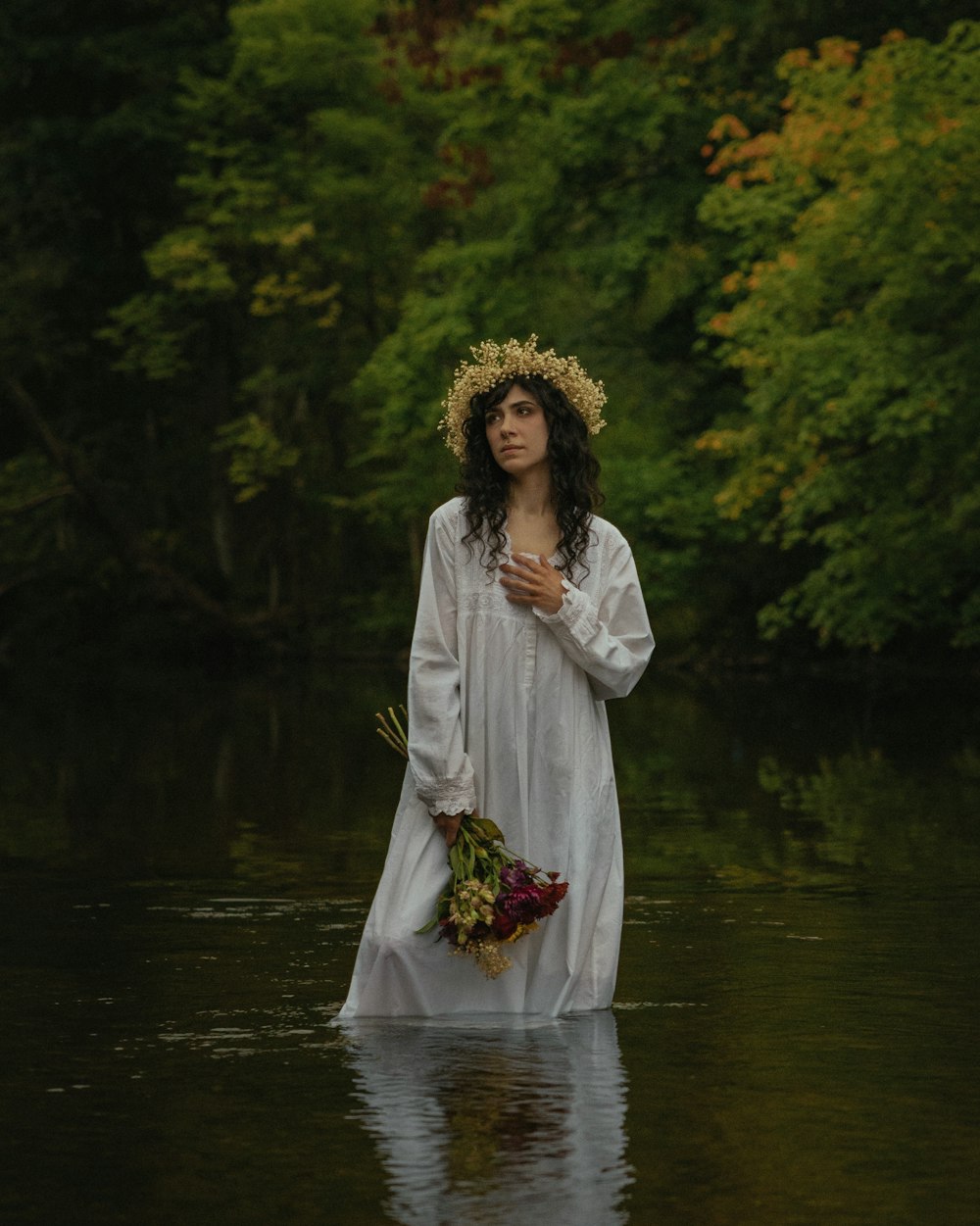 a woman in a white dress standing in a river