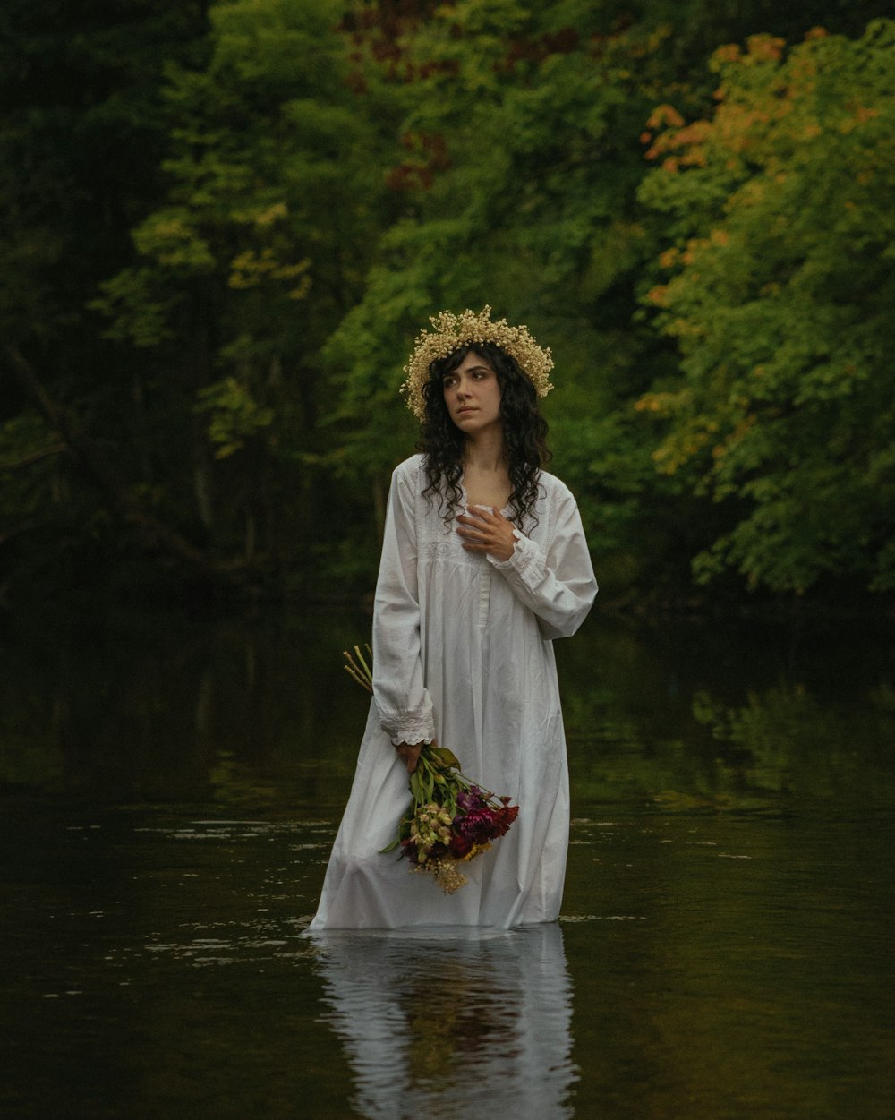 uma mulher em um vestido branco em pé em um rio