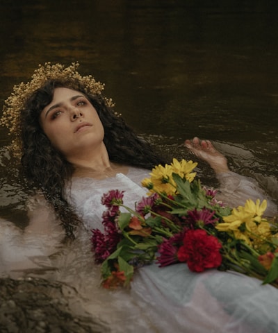 a woman laying in the water with flowers in her hair