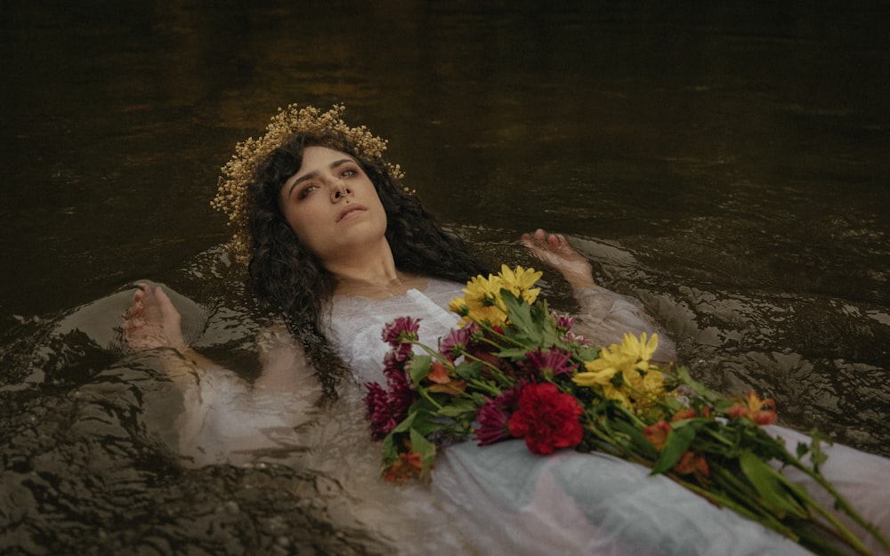 a woman laying in the water with flowers in her hair