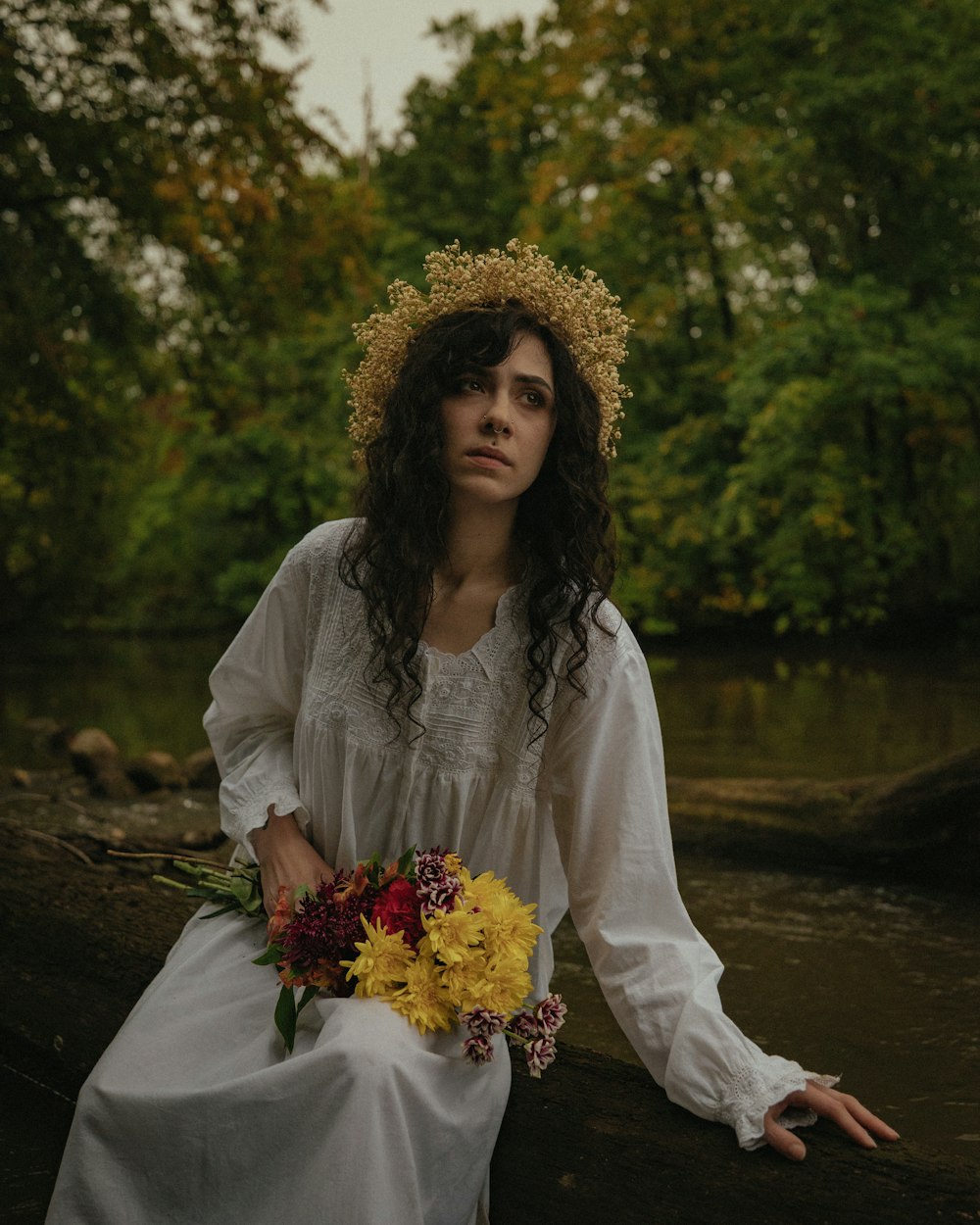 a woman sitting on a log with a bouquet of flowers