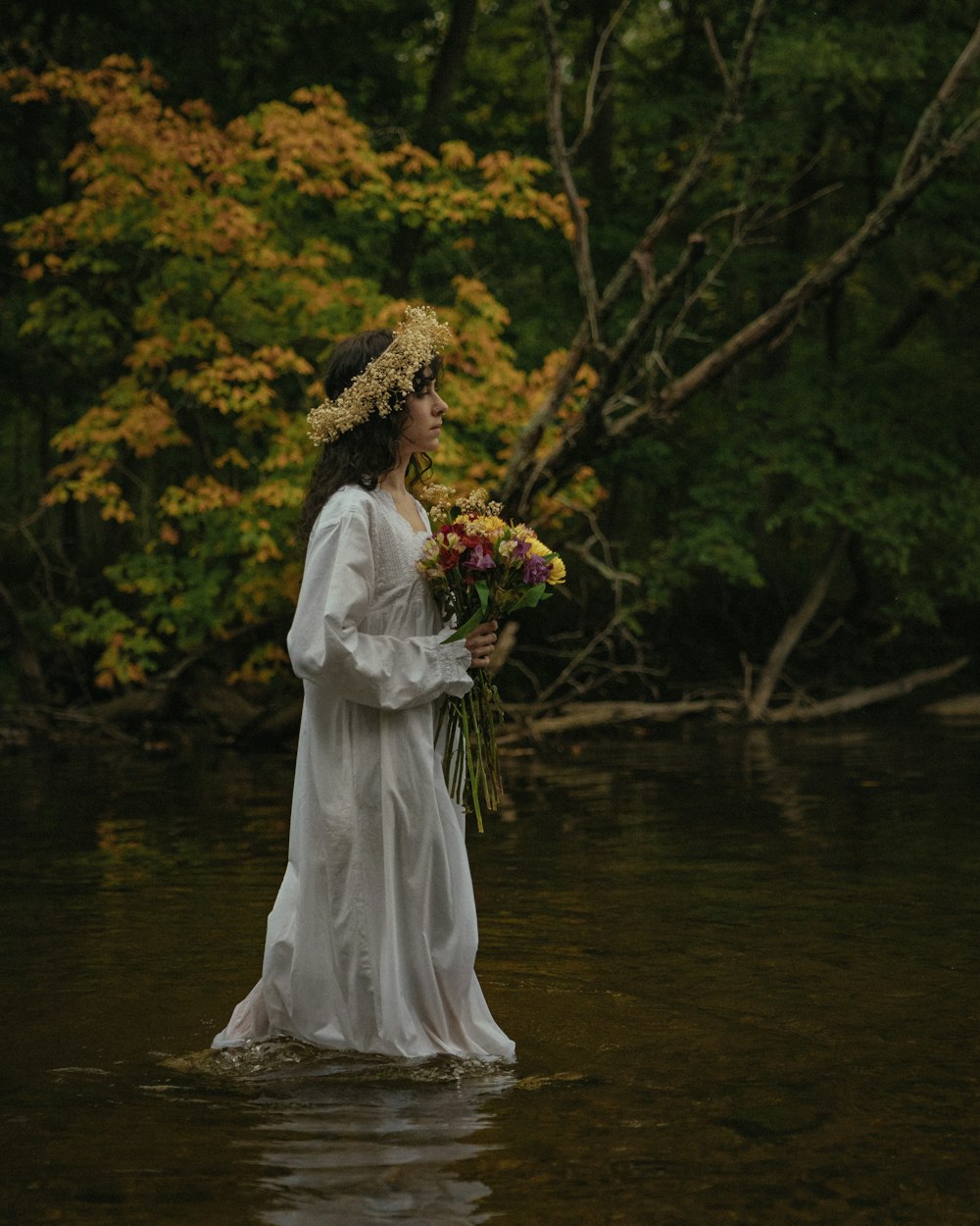 a woman in a white dress standing in a river