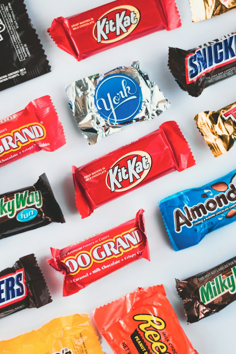 a variety of candy bars lined up on a white surface