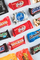 a variety of candy bars lined up on a white surface