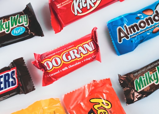 a variety of candy bars lined up on a white surface