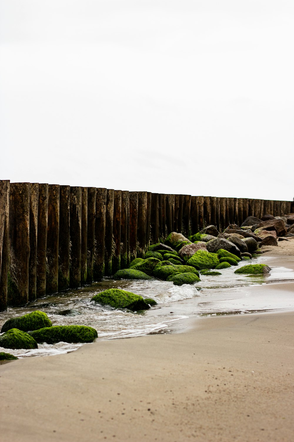 a long wooden fence on a beach next to the ocean