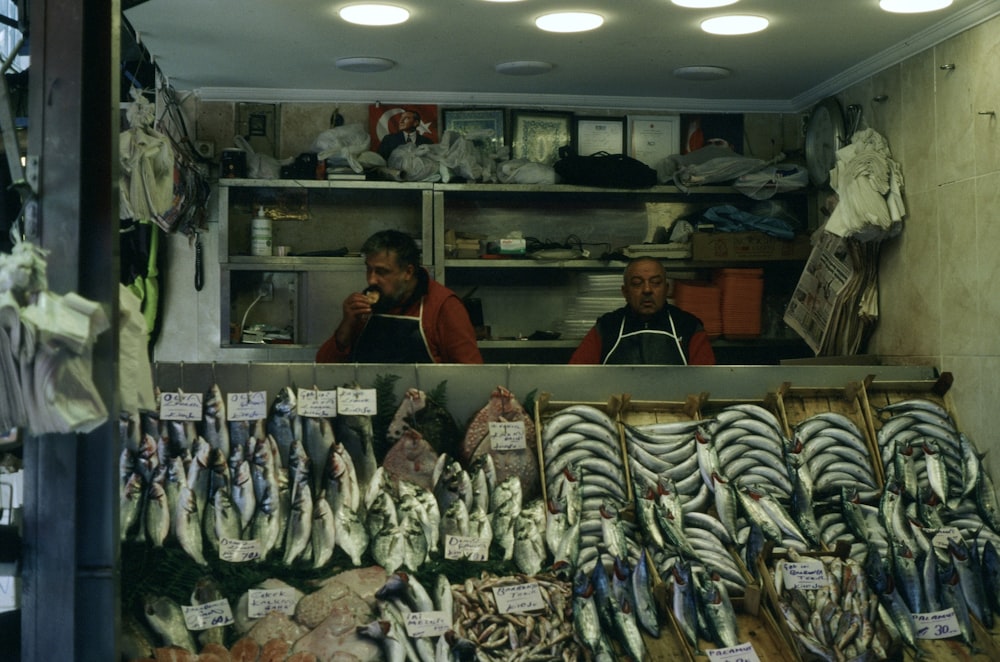 a couple of men standing in front of a display of fish