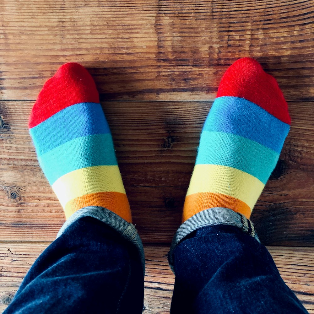a person wearing colorful socks and jeans standing on a wooden floor
