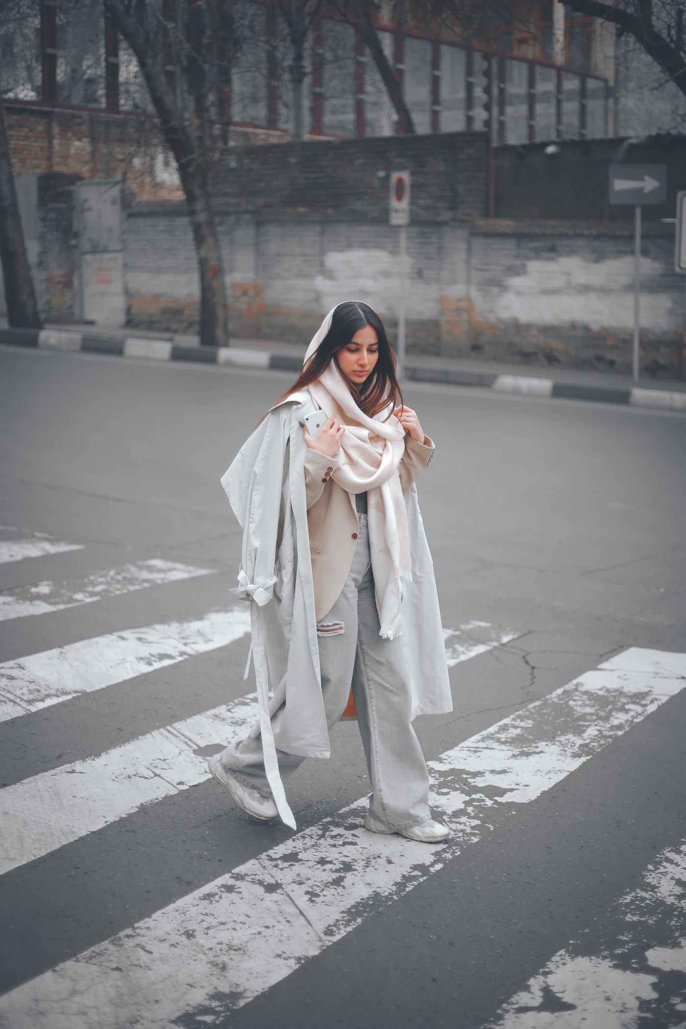 A woman is crossing the street in the rain