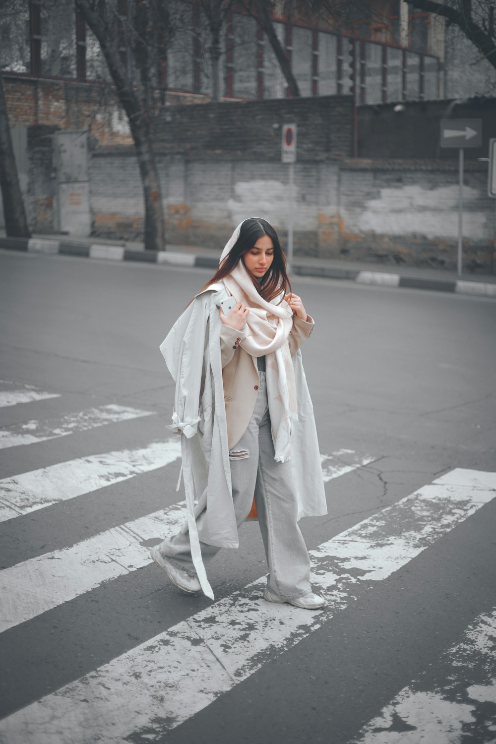 a woman is crossing the street in the rain