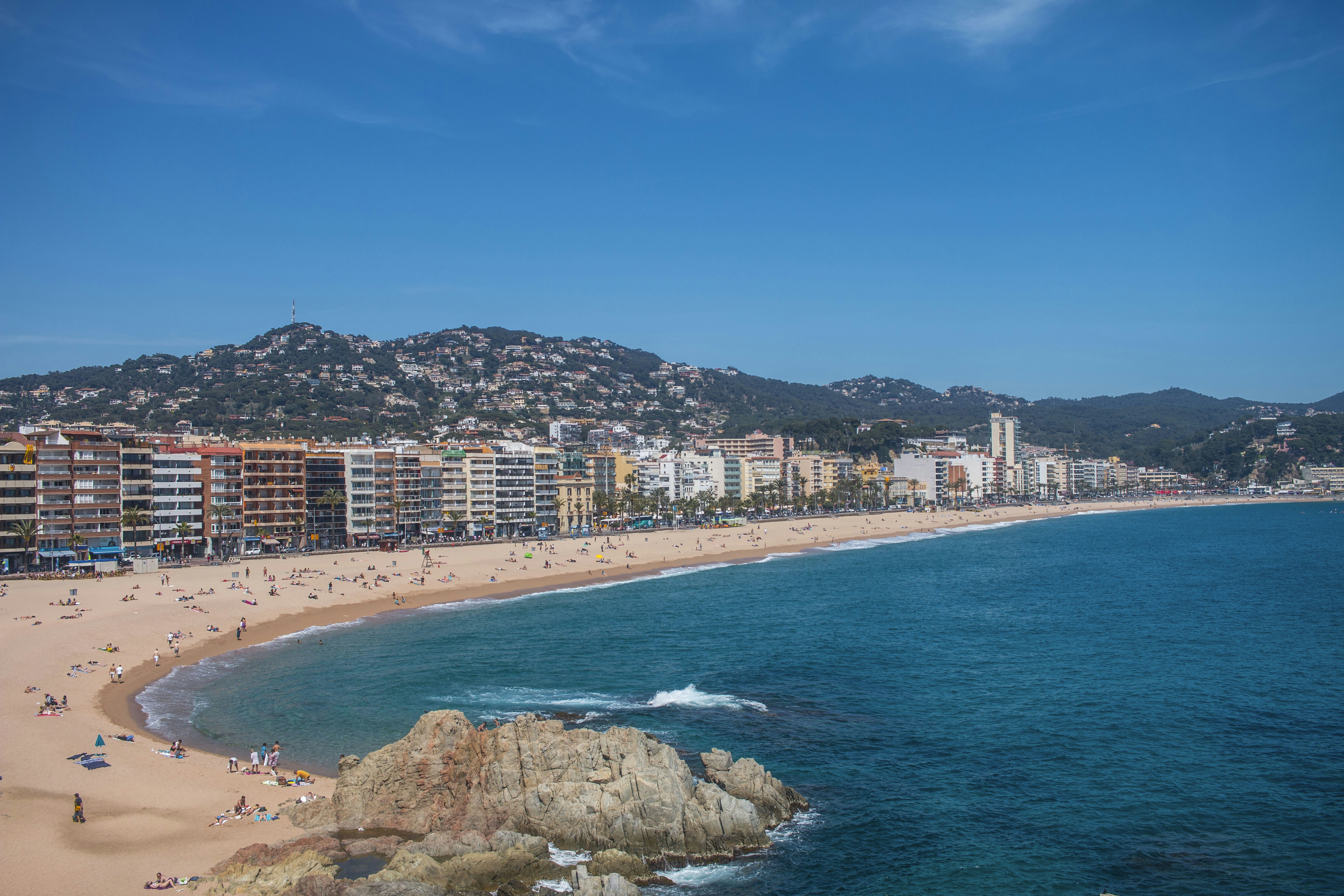 A beach right bu the city with lots of people on it. 
