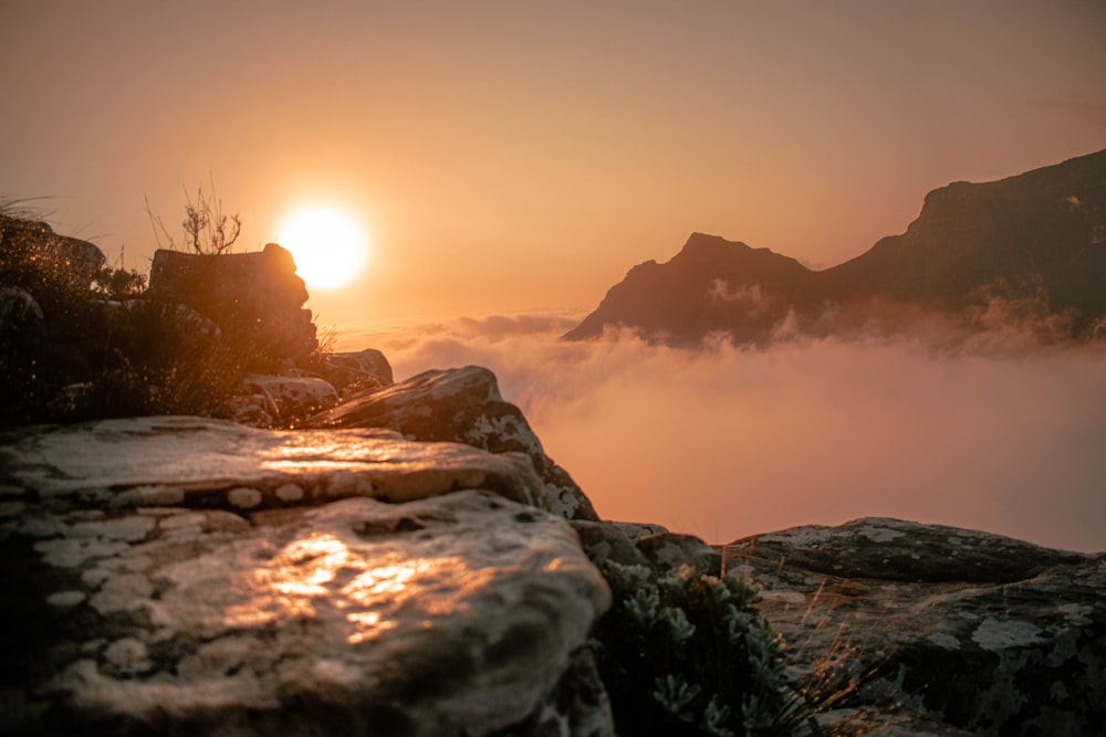 the sun is setting over a foggy mountain range