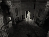 Silhouette of a solitary figure framed by a vast, empty architectural space.