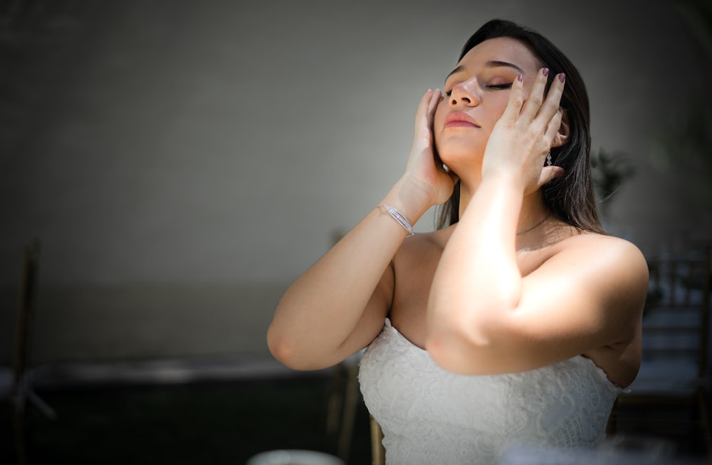 a woman in a white dress holding her hands to her face