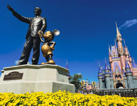 a statue of walt and mickey mouse in front of a castle